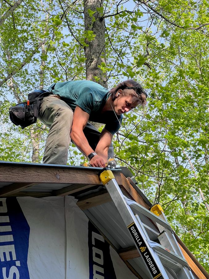Ethan Heck fastening roof metal at the edge of a roof